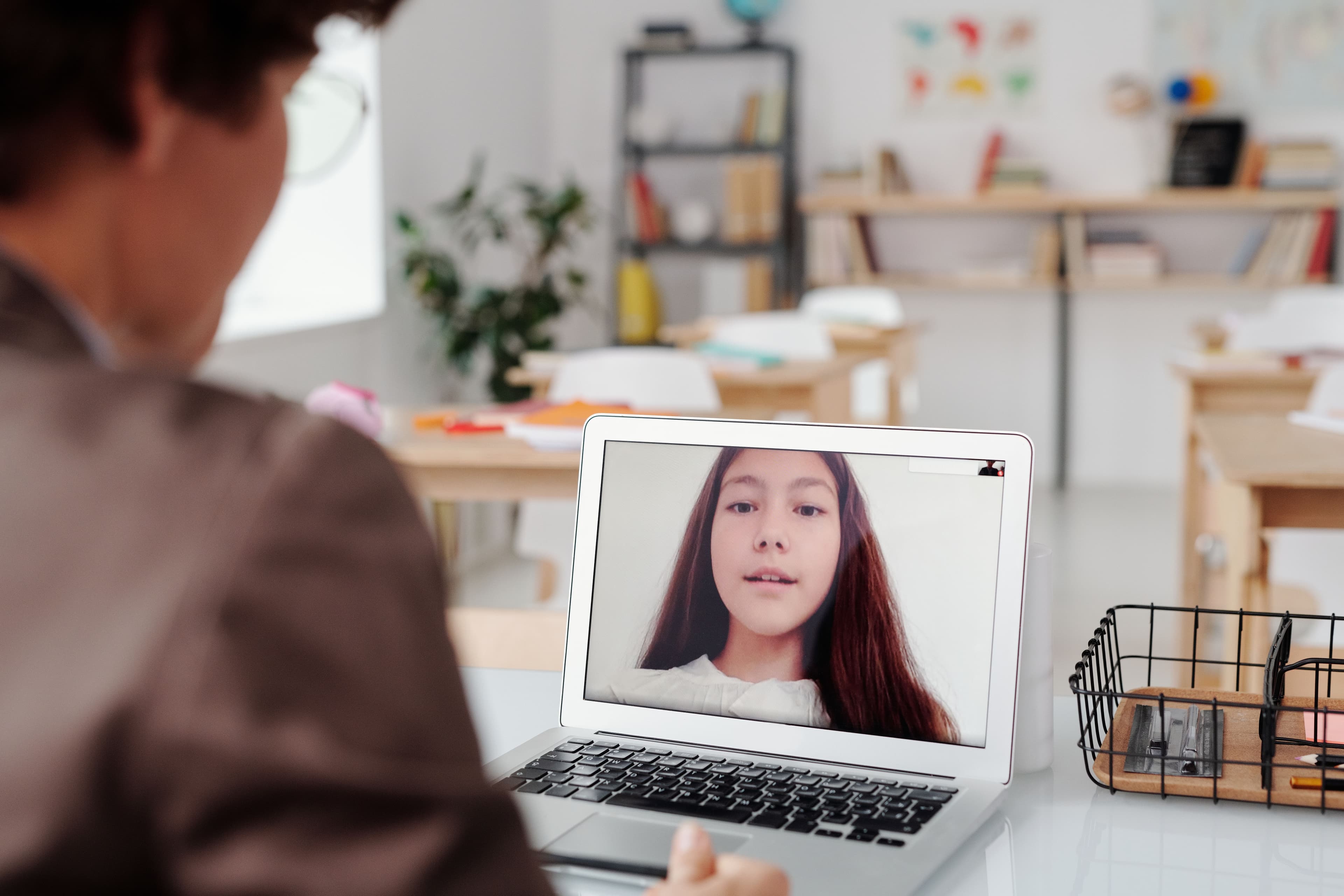 A tutor at a desk, teaching a student over a video call.